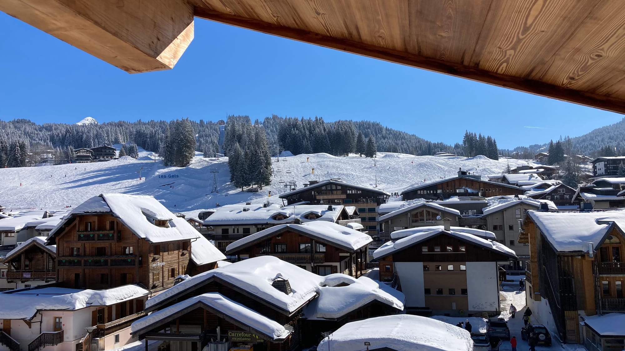 Un balcon avec vue sur le village enneigé et les pistes de ski